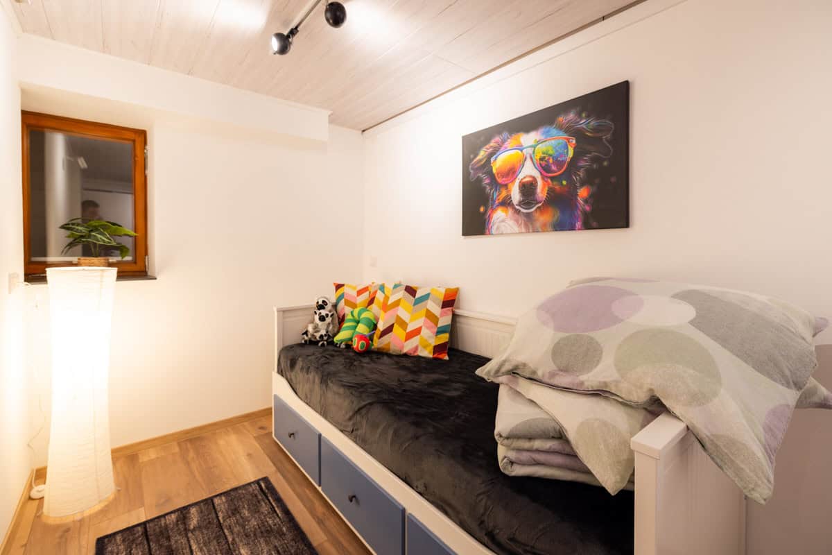 Gemütliches Schlafzimmer mit bunten Kissen und Hund-Poster, ruhige Atmosphäre, Ferienhaus Karl.