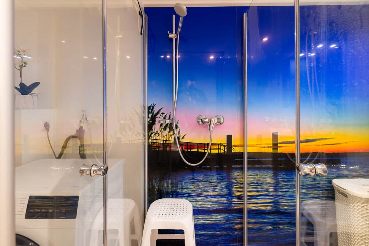 Badezimmer mit Felsenmuster, Blick auf Sonnenuntergang am Wasser, entspannte Atmosphäre.