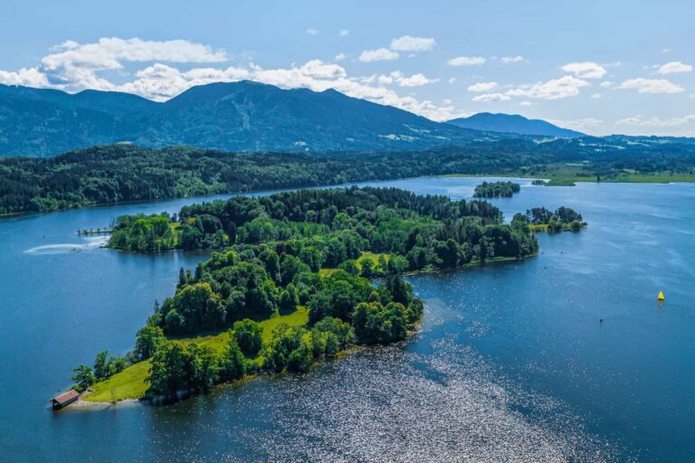 Stimmungsvolles Ferienhaus am ruhigen See mit Blick auf grüne Inseln und Berge in der Natur.